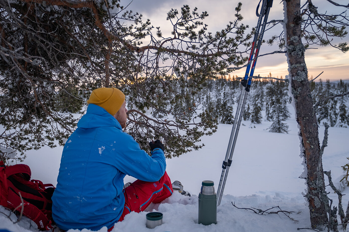Person sitzt im Schnee bei einer Pause im Winter in Lappland